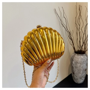 Detail view of a shell-shaped gold evening clutch with a polished metallic mirror finish