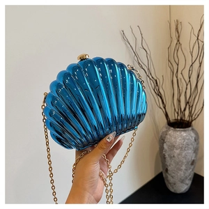 Close-up of blue seashell evening bag with metallic finish and gold chain strap