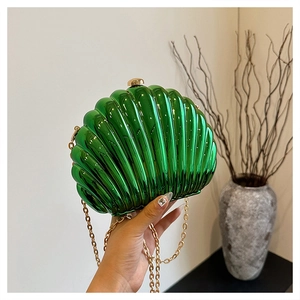 Detail of candy green shell-shaped acrylic clutch bag with gold spherical metal clasp