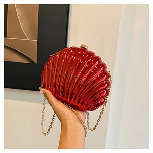 Detail of red shell-shaped acrylic evening bag with mirror finish and gold chain