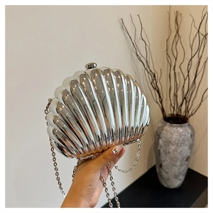 Detail of silver shell evening bag with metallic mirror finish and chain strap