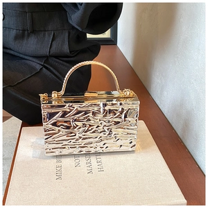 Dettaglio della borsa da sera dorata con trama lavica e manico ad anello glitter