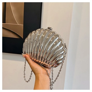 Close-up of a silver shell-shaped evening clutch with metallic texture and chain strap