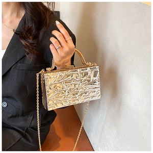 Clutch da sera oro champagne con trama effetto ghiaccio indossata da modella in tailleur