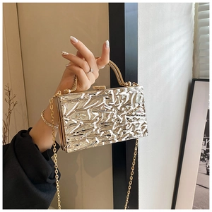 Dettaglio borsa clutch dorata in acrilico con trama a effetto ghiaccio e manico in metallo