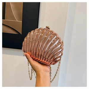 Detail of rose gold shell evening clutch with metallic texture and sleek gold chain strap