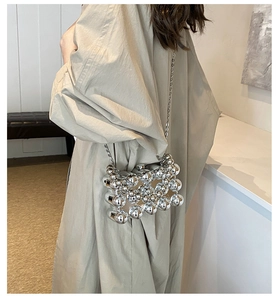 Detailed view of a silver metallic sphere cage bag with a sleek crossbody chain strap