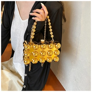 Detail of a gold spherical acrylic clutch bag with metallic beads and chain strap