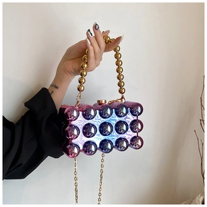 Close-up of holographic gradient ball clutch bag with golden chain and bead handle