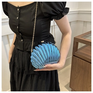 Detailed view of the iridescent blue shell-shaped acrylic bag with gold chain strap