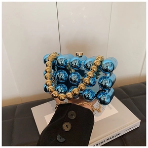 Detail view of blue acrylic box bag with gold beaded handle and 3D spherical texture