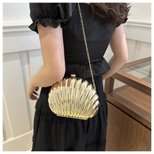Detail of a gold metallic shell clutch bag with mirror finish and chain shoulder strap