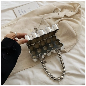 Macro detail of silver egg-shaped metallic clutch with bead handle and chain strap