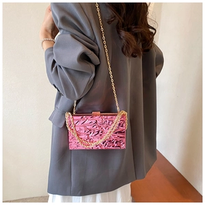 Elegante borsa da sera in acrilico rosa con catena dorata indossata da una modella