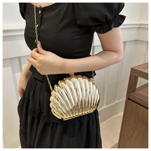 Detail shot of the golden metallic shell clutch bag with a textured finish and chain strap