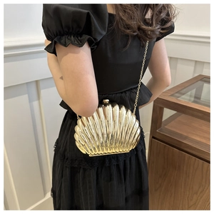 Detailed view of a gold shell-shaped acrylic evening clutch with luxury metallic finish