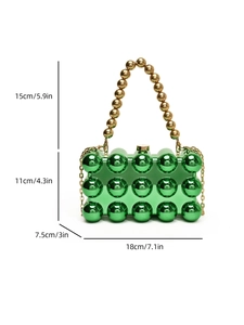 Detail of green acrylic ball handbag with golden bead handle and mirror finish texture