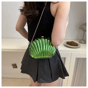 Close-up of green metallic shell bag with gold chain strap on a model outfit