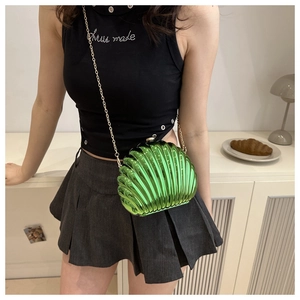 Detail of green shell-shaped acrylic bag with pleated texture and gold chain strap