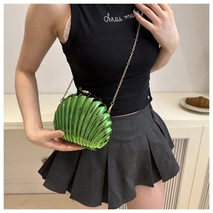 Detailed view of a bright green shell-shaped acrylic clutch with gold metal chain strap