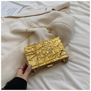 Dettaglio della pochette in acrilico dorato con trama a crepe e catena in metallo