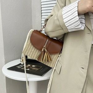 Détail du sac bandoulière en paille avec rabat en cuir brun, glands et sangle en coton