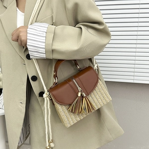 Vue détaillée du sac à main en paille avec rabat en cuir et pompons décoratifs