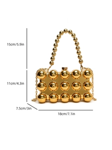 Close-up of golden acrylic evening bag with metallic studs and spherical handle