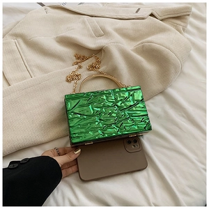 Dettaglio della borsa rigida in acrilico verde smeraldo con trama craquelé e manico oro