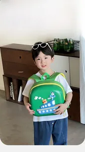 Toddler wearing green hard-shell backpack with 3D ship design and yellow zipper detail