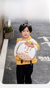 Toddler backpack with 3D donut design and 'lucky' text worn by a boy on the street