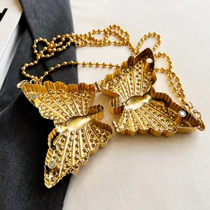 Detalle del bolso de mano mariposa de metal dorado con estructura interna y cierre imán