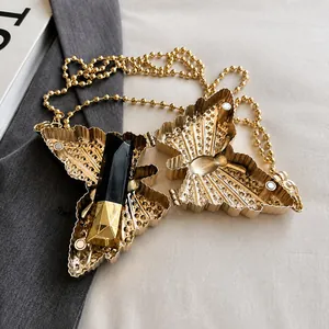 Detalle de mini bolso de mariposa dorada con textura radial y elegante cadena de perlas