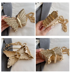 Vistas detalladas de un bolso de mano de metal con forma de mariposa dorada.