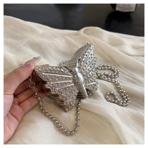 Detalle de bolso de noche de mariposa plateado con pedrería y correa de cuentas