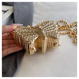 Detalle de un bolso de mariposa dorado con cristales blancos y cadena de cuentas