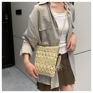Detail of bohemian straw crossbody bag with crochet flower patterns and tassel charm