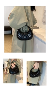 Detail of glossy black quilted box bag featuring round handle and gold chain strap