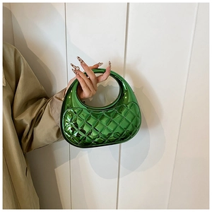 Detail of emerald green quilted acrylic evening box bag with circular hollow handle
