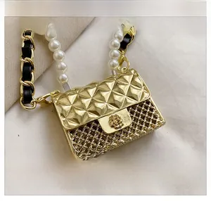 Detail of a mini gold quilted bag featuring a hollow grid design and pearl chain strap