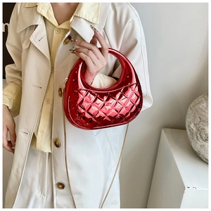 Close-up of red quilted acrylic box bag with glossy finish and gold chain strap