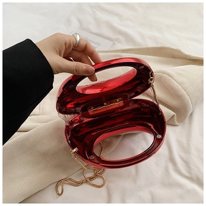 Detail of red acrylic evening clutch with gold chain strap and magnetic closure
