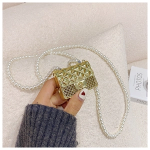 Detail of a mini gold quilted crossbody bag with decorative white pearl chain strap