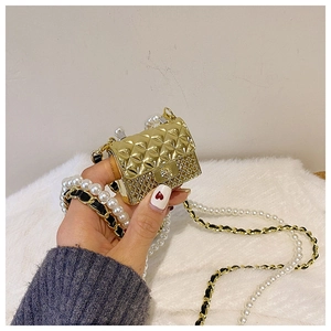 Close-up of golden mini quilted bag accessory with elegant pearl and leather chain strap