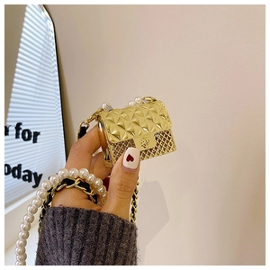 Detailed view of golden mini bag with quilted pattern and elegant pearl chain handle