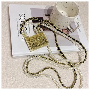Detail of mini gold quilted crossbody bag with pearl strap and metal chain