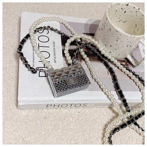 Macro detail of silver quilted mini bag with crystal studs and pearl chain strap