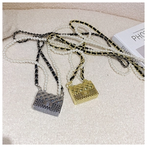 Detail of mini quilted bags in gold and silver with pearl chain on soft fabric