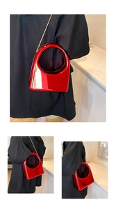 Gros plan d'un sac à main en cuir verni rouge brillant avec poignée ronde et chaîne en métal