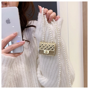 Detailed close-up of golden quilted mini bag featuring pearl chain and floral clasp